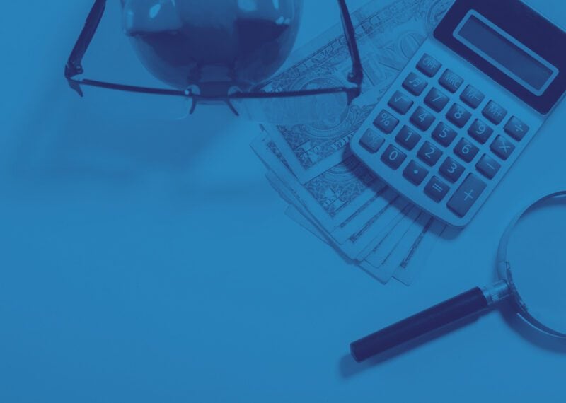 Bulgarian personal income tax - residence and rates - calculator, magnifying lens, pen, money, glasses - blue toned image.